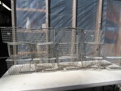 several metal baskets sitting on top of a white table next to a window with mesh covering