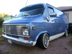 an old blue van parked in front of a house