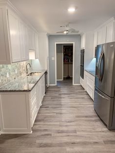 a large kitchen with white cabinets and stainless steel appliances, along with marble counter tops