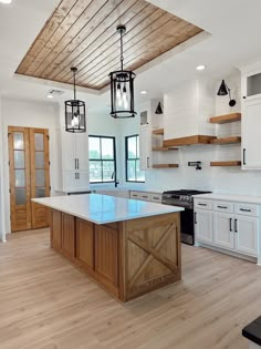 a large kitchen with white cabinets and wood flooring on the walls, along with an island in the middle