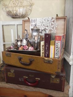 two suitcases stacked on top of each other with tea pots and books in them