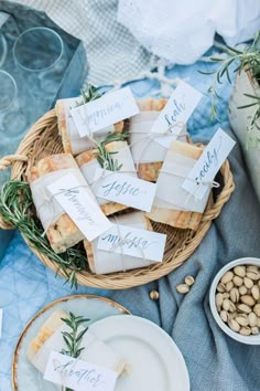 a table topped with lots of food and place cards on top of plates covered in paper