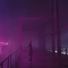 a person standing on a bridge in the dark with purple light coming from behind them