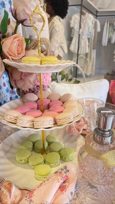 three tiered trays with macaroons and flowers on them sitting on a table