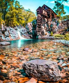 a wooden structure sitting on top of a rocky hillside next to a river filled with rocks