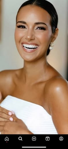 a woman in a white dress smiling and holding her hands together