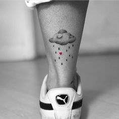 a woman's foot with a tattoo on it and an umbrella in the rain