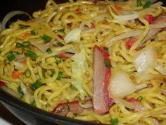 noodles and vegetables are being cooked in a skillet