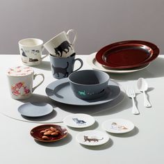 a table with plates, cups and spoons on it that have animals painted on them