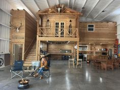 a woman sitting in a chair inside of a wooden building with lofts on the roof