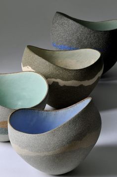 four bowls sitting side by side on a white surface, each with different colors and shapes