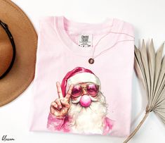 Comfort Colors Shirt, Pink Santa Shirt, Blowing Bubble Christmas Shirts, Santa with Sunglasses Christmas Tee, Santa Christmas Shirt Welcome to Opia Apparel. Here you will find personalized t-shirts for your friends and family that will make you smile. We want to make everyone smile with our cute , stylish and trendy graphic T-shirts. We can assured you this shirt will be perfect gift whether you will buy it yourself or for someone else. ✷ About Us ✷ This new business was founded by a small family. Your t-shirt will be made with love. Thank you for choosing us. ✷ Sizing and Color Guidelines✷ Unisex t-shirt size: S | M | L | XL | 2XL | 3XL We use Comfort Colors Heavyweight brand t-shirts for all listings where Comfort Colors is mentioned in the title. These shirts are unisex and designed to Pink Christmas Shirt, Bubble Christmas, Pink Santa, Santa Sweatshirt, Santa Shirt, Christmas Tshirt, Santa Shirts, Blowing Bubbles, Funny Christmas Shirts