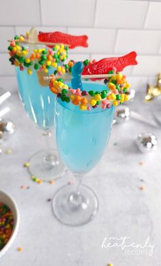 two glasses filled with blue liquid and candy sprinkles on top of a table