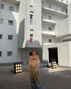 a woman standing in front of a white building with lights on it's sides