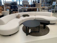 a white sectional couch sitting on top of a floor next to a black coffee table