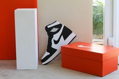 two nike shoes sitting next to each other in front of an orange and white box