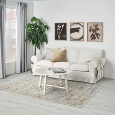 a living room with white couches and paintings on the wall