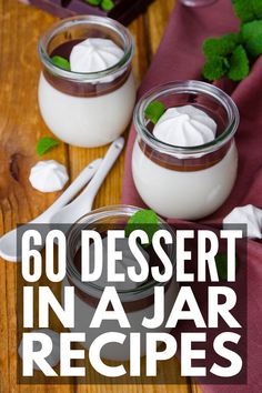 two jars filled with desserts sitting on top of a wooden table next to utensils