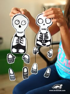 a girl holding up cut out skeleton decorations