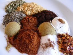 an assortment of spices on a white plate