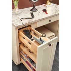 an open drawer with tools and other items in it on top of a counter next to a clock