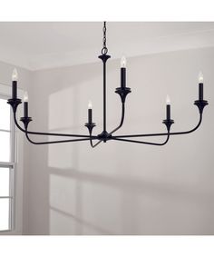 a black chandelier hanging from the ceiling in a room with white walls and windows