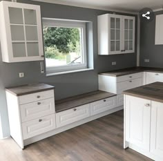 an empty kitchen with white cabinets and wood floors