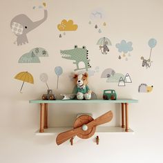 a teddy bear sitting on top of a shelf in front of a wall with animal decals