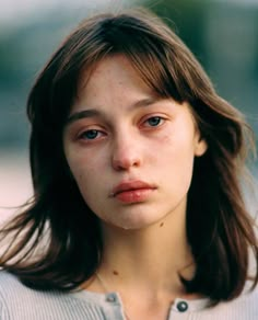 a close up of a person wearing a sweater and looking at the camera with a serious look on her face