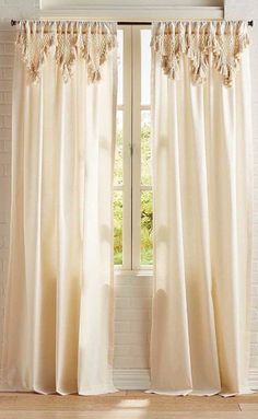 an open window with white curtains in front of a brick wall and wooden flooring