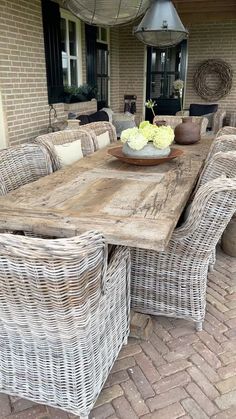 an outdoor dining table with wicker chairs and a bowl of flowers on the table