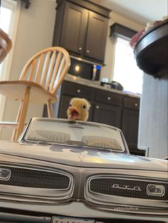 a toy car in the middle of a kitchen with a teddy bear sitting on top