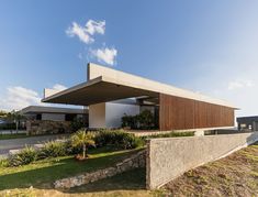 the house is made out of concrete and has an unusual roof that extends into the yard