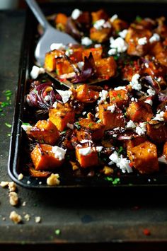 a pan filled with cooked vegetables and feta cheese on it's side, ready to be eaten