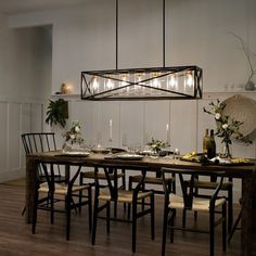 a dining room table and chairs with lights hanging from the ceiling