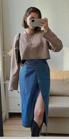 a woman taking a selfie in front of a mirror wearing a skirt and sweater