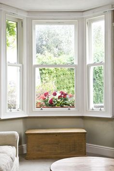 a living room filled with furniture and a large window next to a wooden coffee table