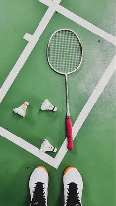 a tennis racquet and shoes on a green court with white lines around it