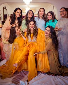 a group of women in yellow outfits posing for a photo on a bed with their arms around each other