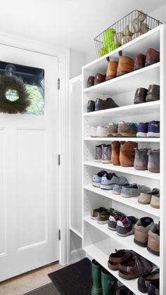 a bunch of shoes that are on some shelves in a room with a door and a black rug