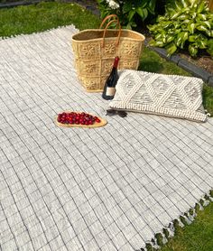 a picnic blanket with a bottle of wine on it next to a basket full of cherries