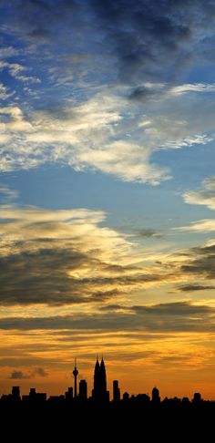 an airplane is flying in the sky at sunset with clouds above it and buildings below