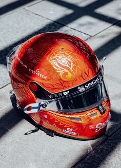 a red helmet sitting on top of a cement floor next to a shadow from the sun