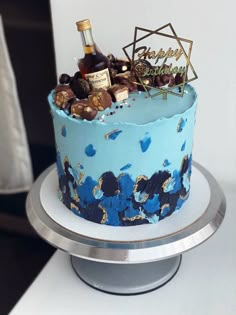 there is a blue cake with gold decorations on the top and a bottle of wine in the middle