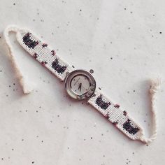 a watch is sitting on top of a piece of white fabric that has been stitched together