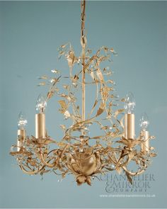 a gold chandelier with five candles hanging from the bottom and one light on top