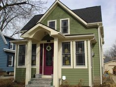 a green house with white trim and red door