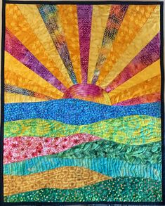 a quilted wall hanging with the sun setting over water and hills in the background