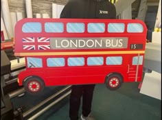 a man holding up a cardboard london bus