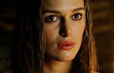 a woman with long hair and blue eyes looks at the camera while wearing a necklace